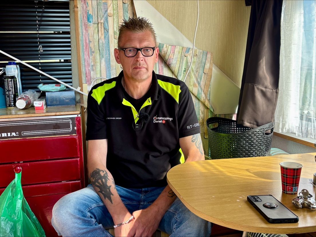 Henk zit op de bank in zijn caravan.