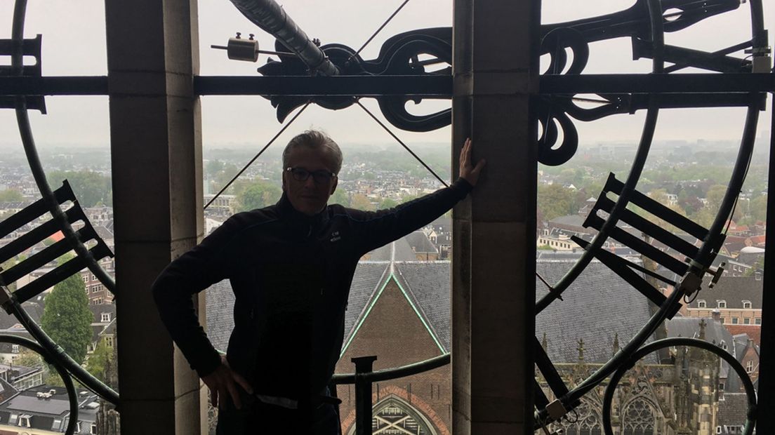 Jaap van Engelenburg in silhouet achter een wijzerplaat van de Domtoren.