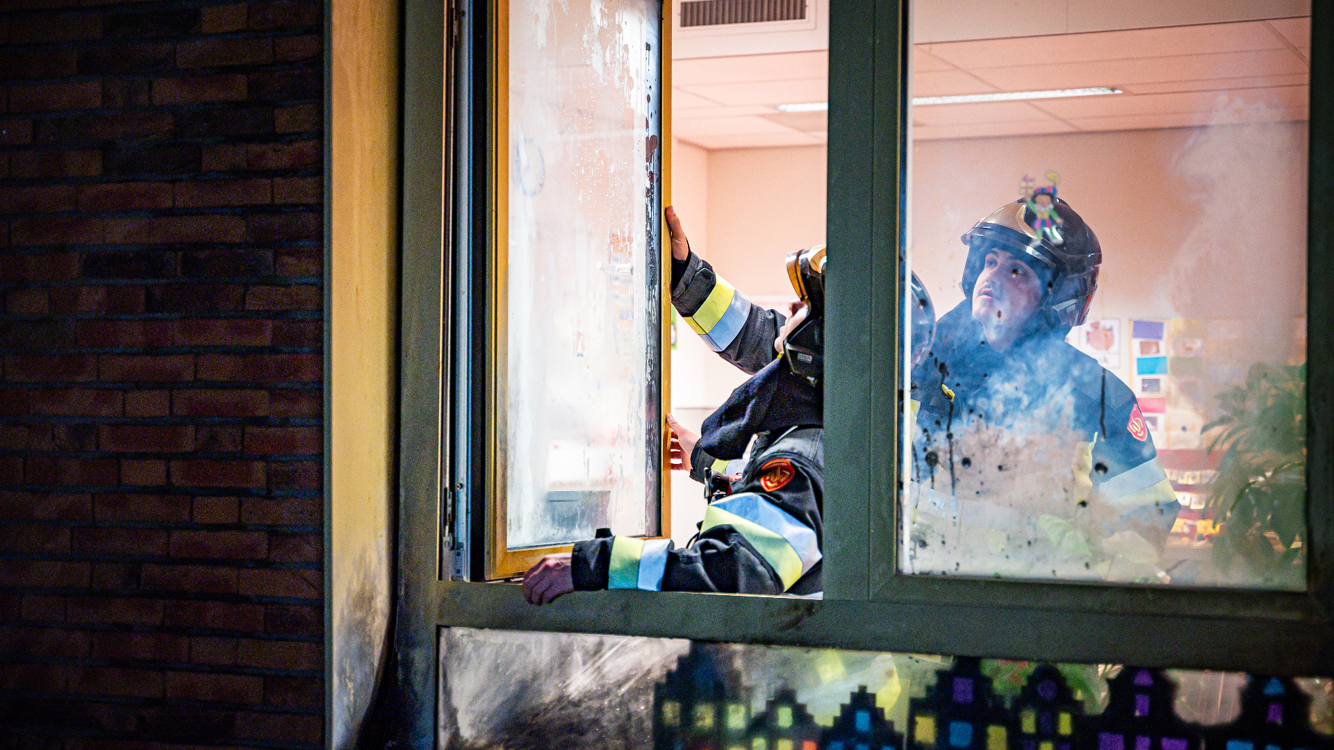 De brandweer onderzoekt na de explosie de ruit die beschadigd raakte