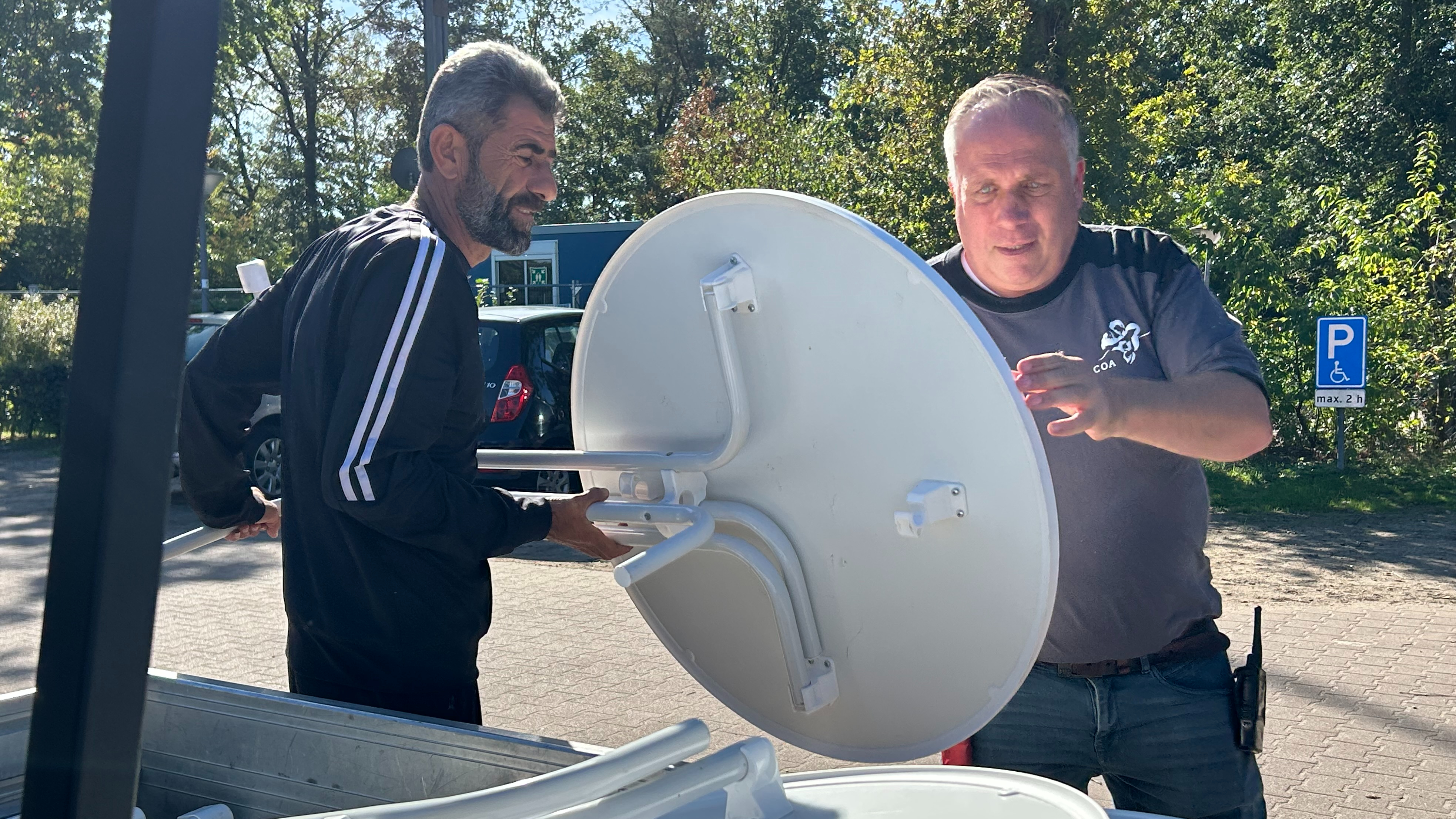 Bewoner Achmed en terreinbeheerder Gert zetten de tafels klaar voor de open dag.