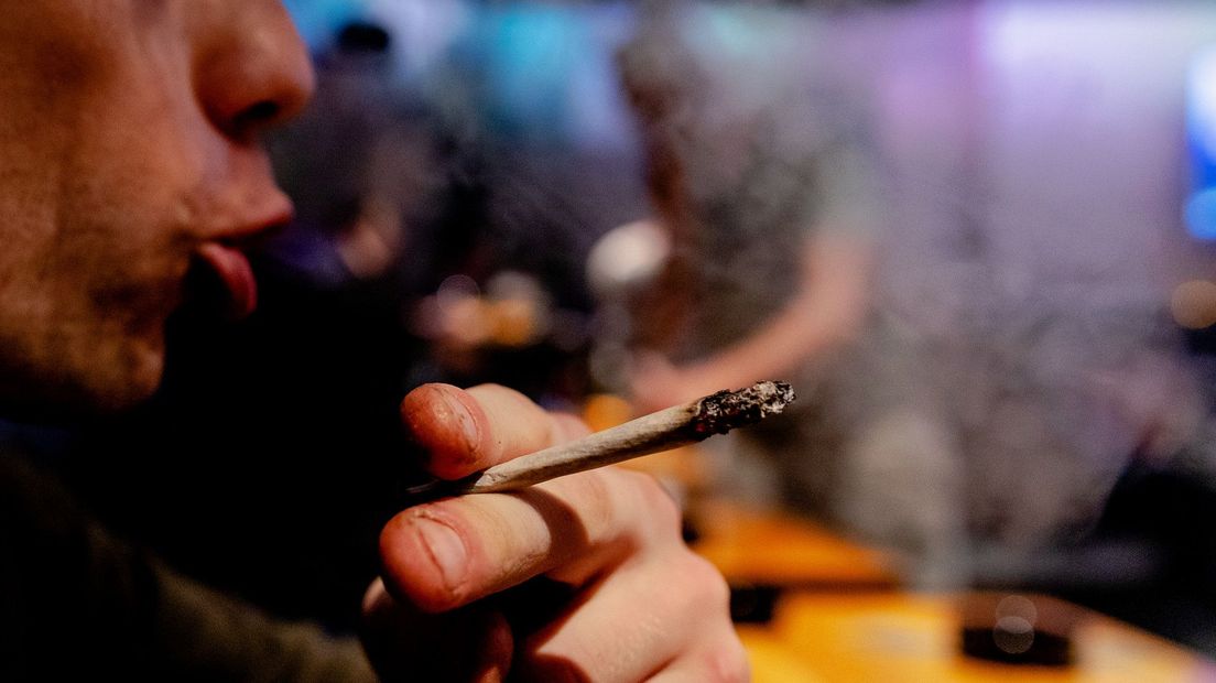 Een bezoeker van een Haagse coffeeshop rookt een joint