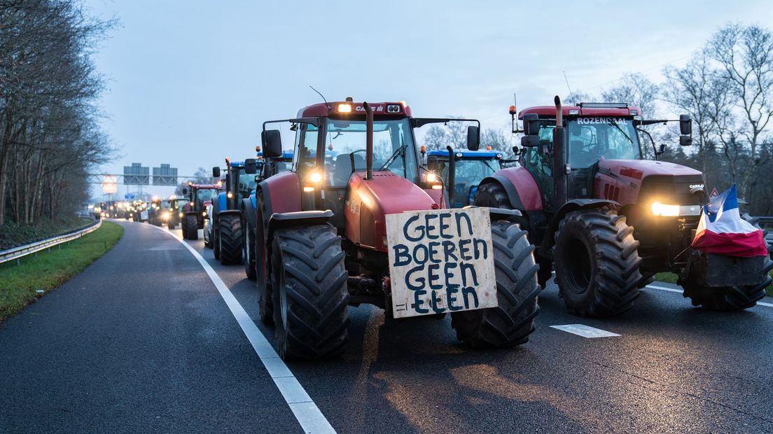 Boeren blokkeren de snelweg met hun trekkers waar protestleuzen op te zien zijn