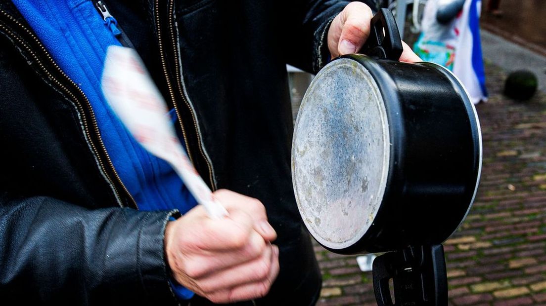 De deelnemers protesteren met potten en pannen tegen het coronabeleid.