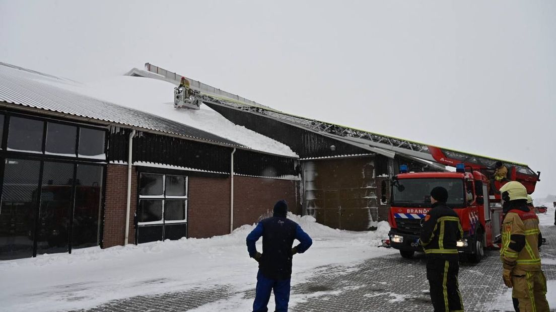 De brandweer verwijdert een sneeuwduin van het dak van een boerderij in Vriezenveen