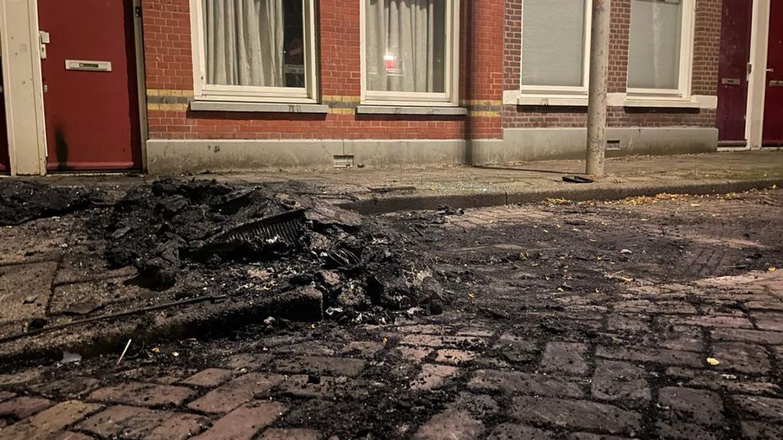 Een zwartgeblakerde parkeerplaats na de autobrand in de Zusterstraat