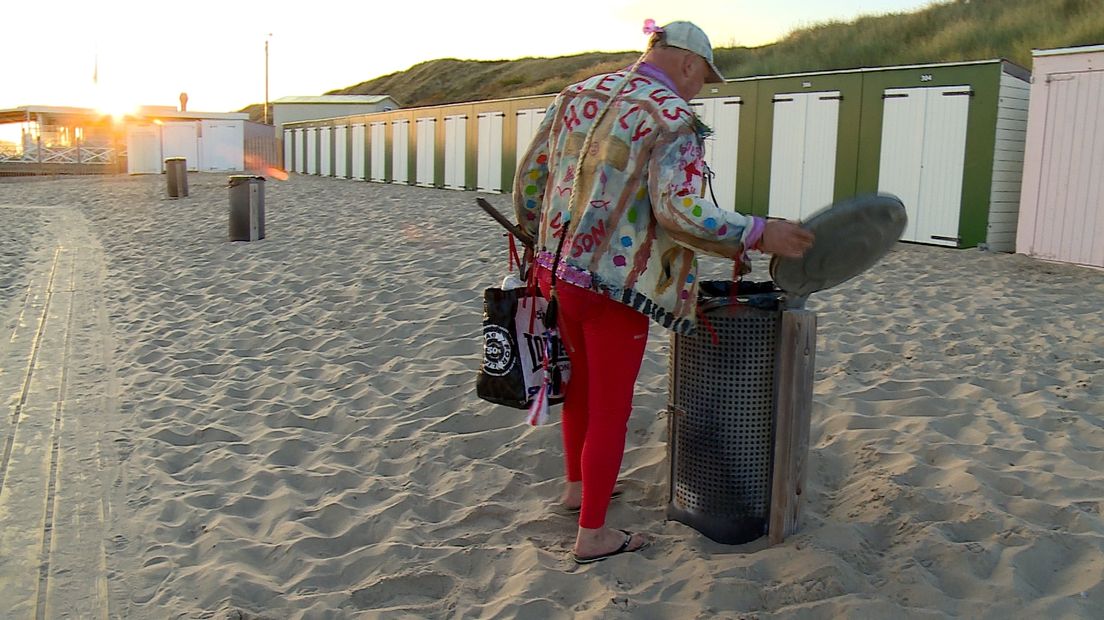 Hendrikse haalt een fles uit een vuilnisbak op het strand van Domburg