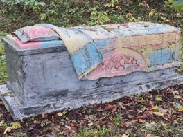 Grafzerk met blauwroze deken en kussen op begraafplaats: van wie is die?