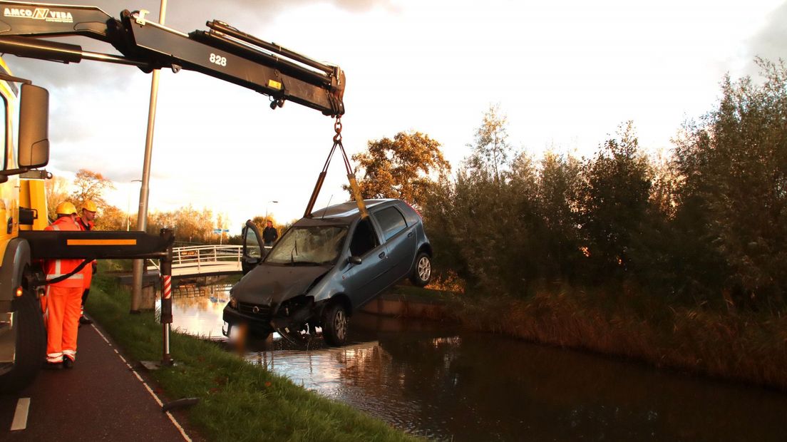Een personenauto wordt in Maasland uit het water getakeld door een bergingsbedrijf