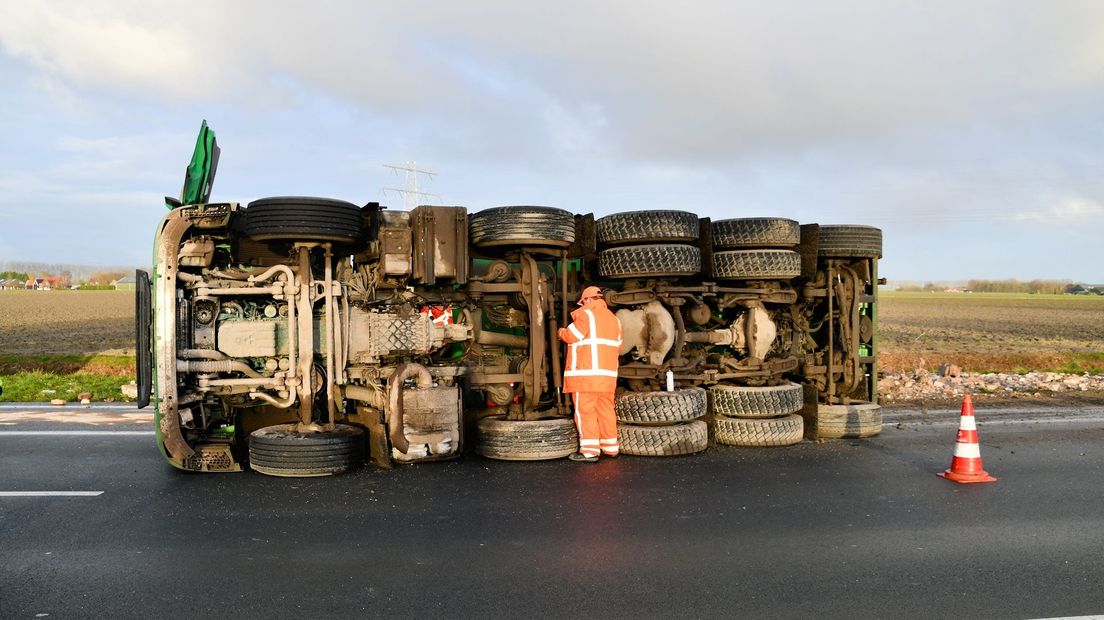 De vrachtwagen ligt omgekanteld op de weg