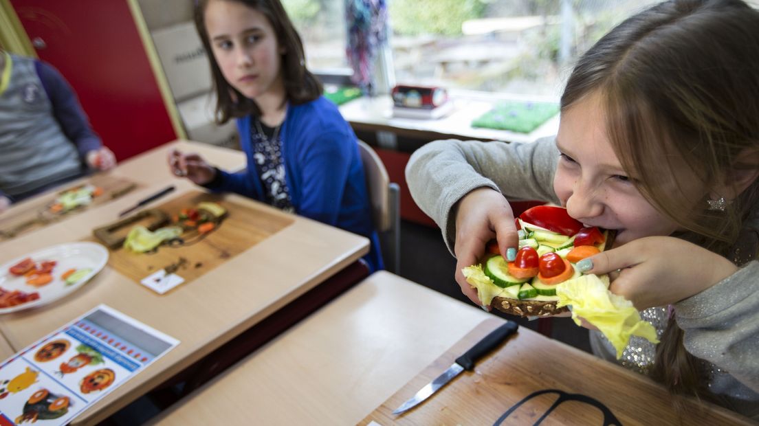 Een leerling neemt op school een hap uit een gezond belegde boterham