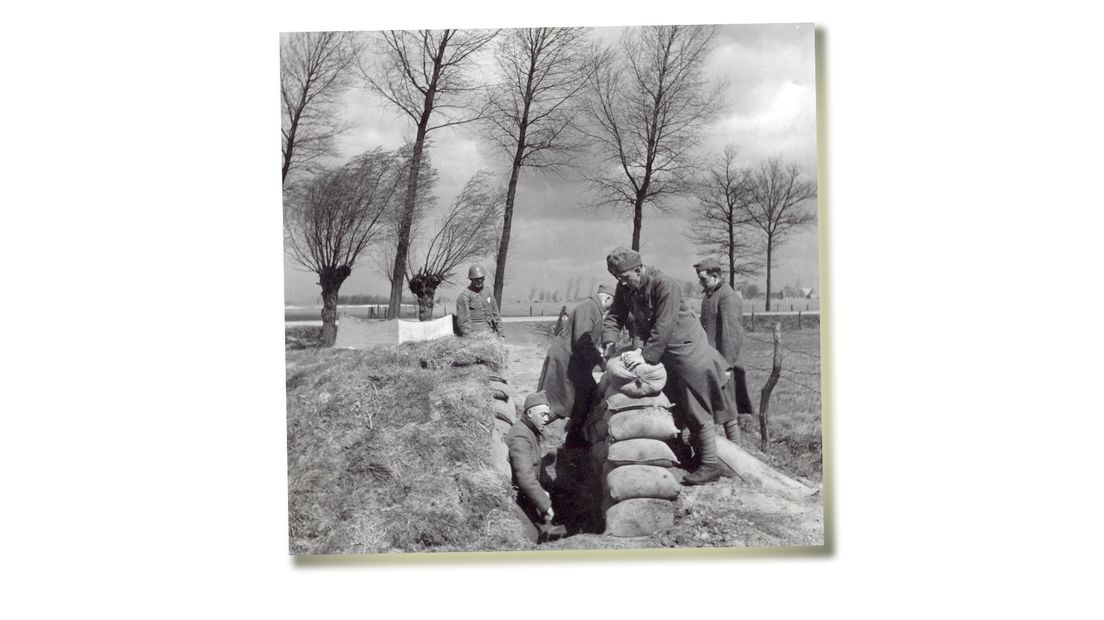 Met zandzakken leggen Nederlandse soldaten een stelling aan in de Grebbelinie.