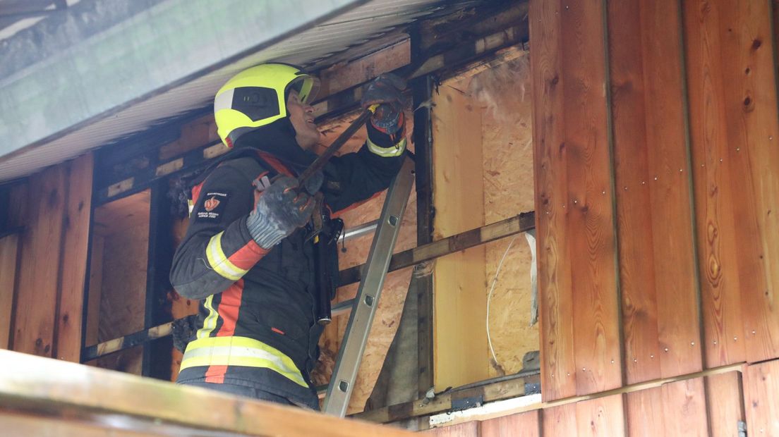 De brandweer heeft een deel van de muur opengebroken om te onderzoeken wat er in brand staat