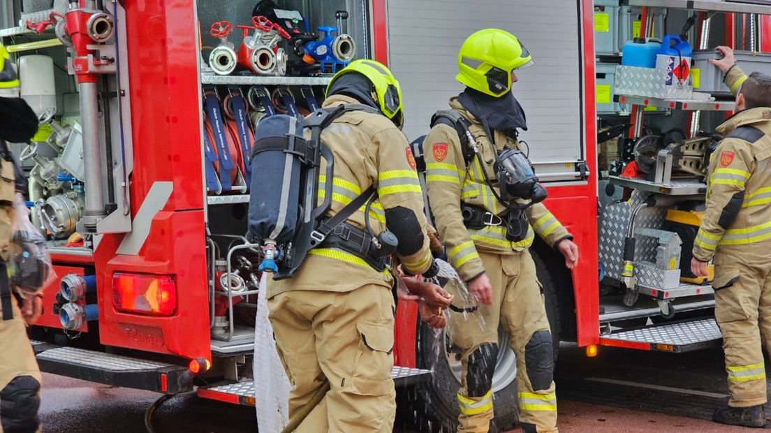 De brandweer helpt een van de betrokkenen bij een keukenbrand met koelen.