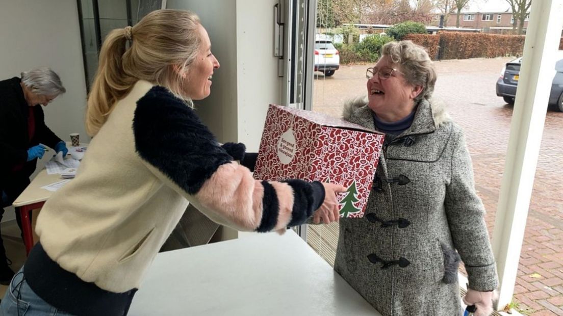 Linda deelt een kerstpakket uit aan een klant van de voedselbank