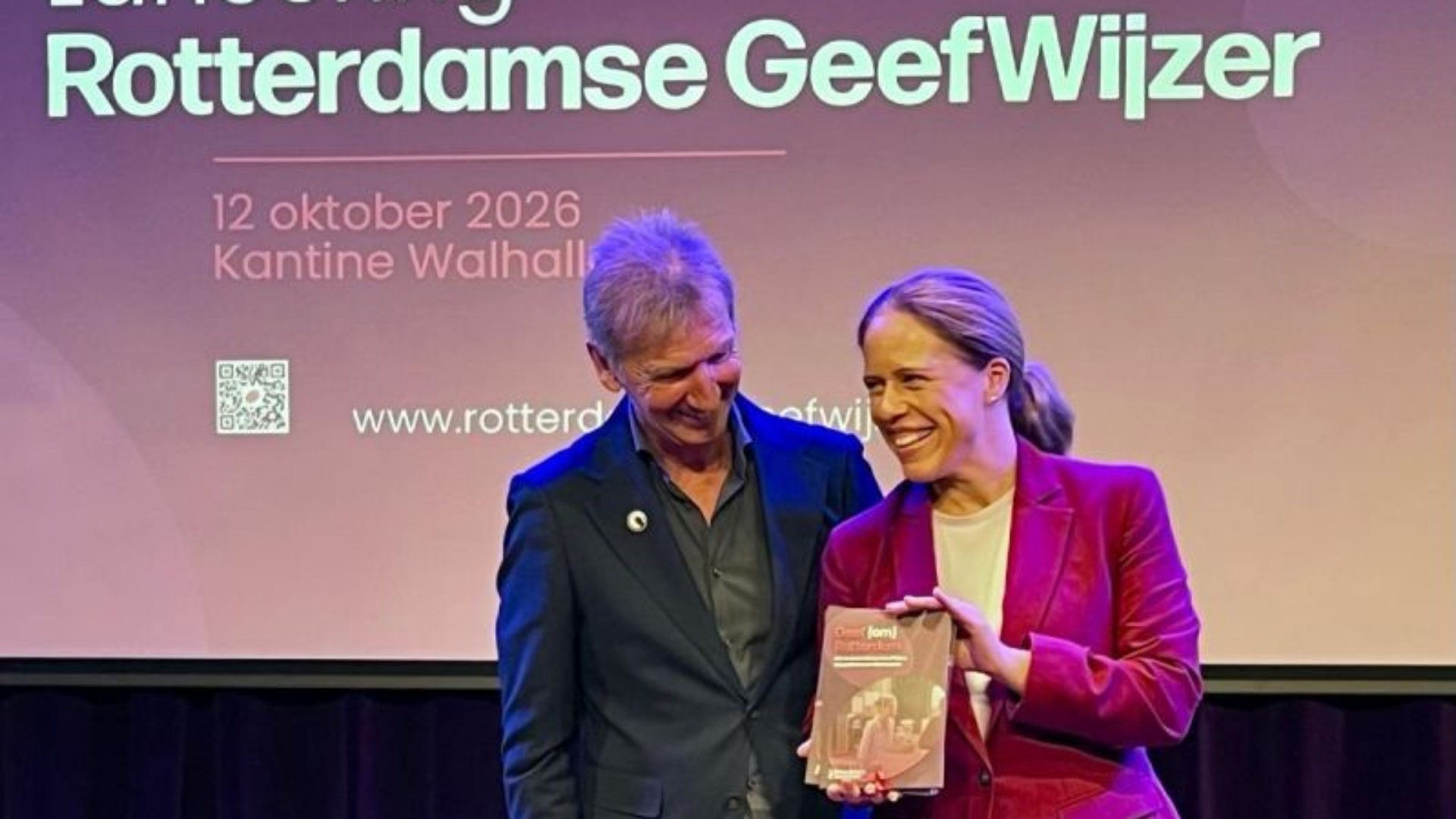 Burgemeester Schouten nam maandagavond de eerste brochure van de Rotterdamse Geefwijzer in ontvangst.