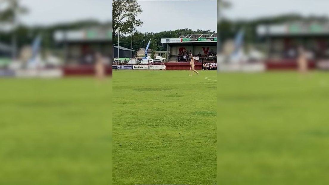 In zijn adamskostuum liep de man met geheven armen over het veld.