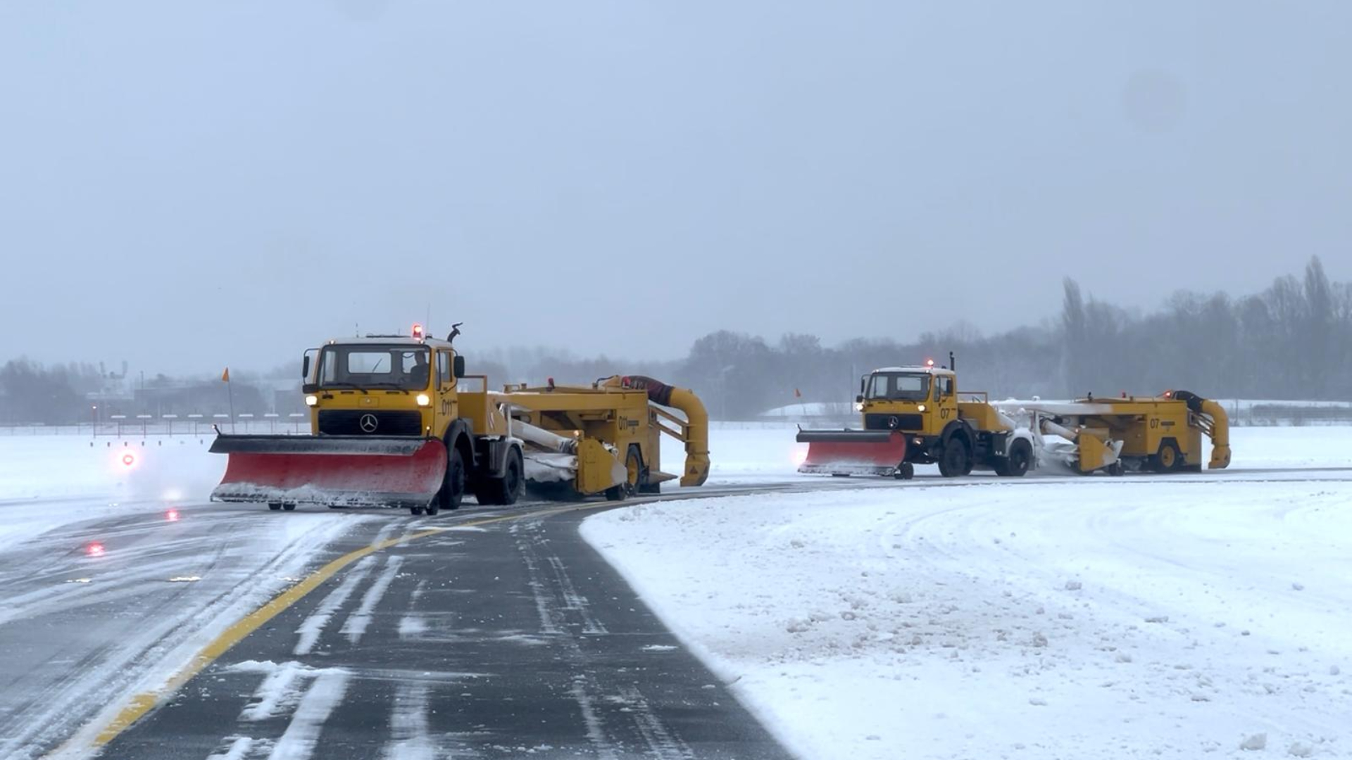 Sneeuwschuivers aan het werk op de landings- en startbaan.