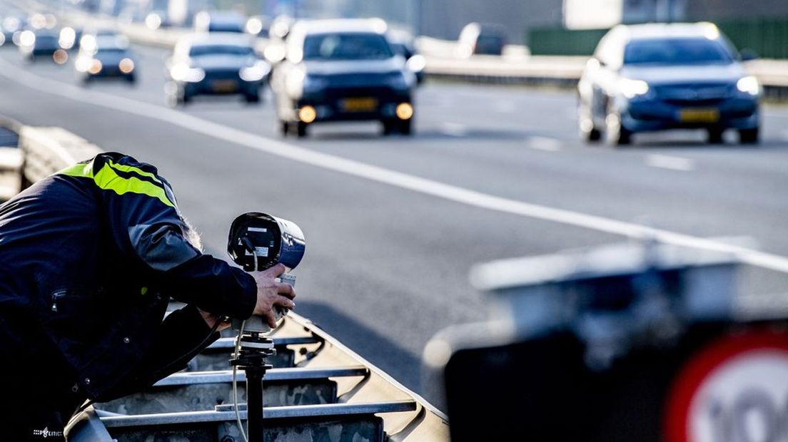 Een politieagent zet een mobiele flitspaal klaar op archiefbeeld. Foto ter illustratie.