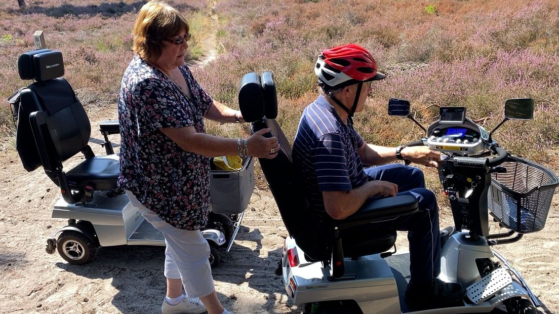 Irene helpt Johan een handje als zijn scootmobiel klem zit in een boomwortel