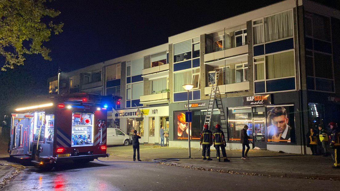 De brandweer evacueert een bewoner van het appartementencomplex.
