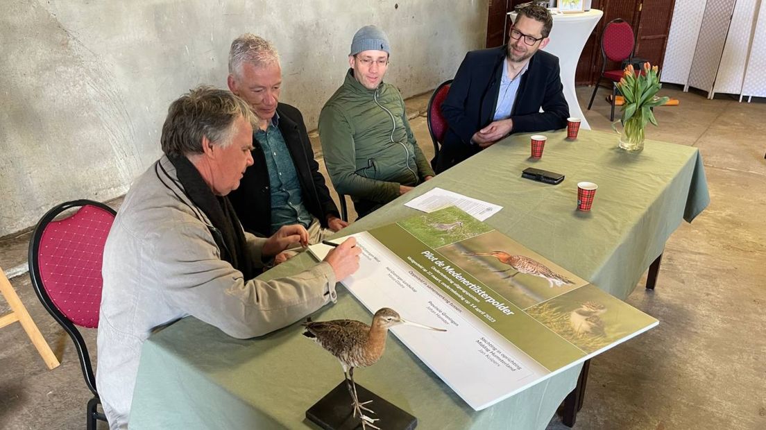 Freek Nieuwenhuis zet zijn handtekening, naast hem vlnr Marco Glastra, Jan Kuipers en gedeputeerde Johan Hamster