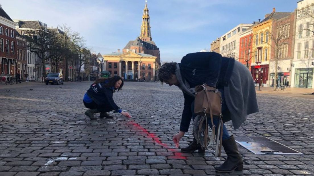 Initiatiefnemers van de actie bezig met het maken van een spoor rood zand op de Vismarkt richting de Nieuwstad