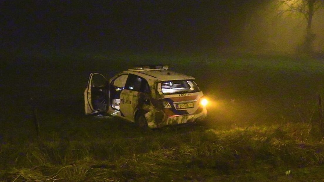 De beschadigde politieauto in het weiland.