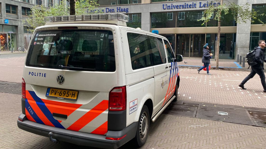 Een politiebus staat voor de ingang van het universiteitsgebouw