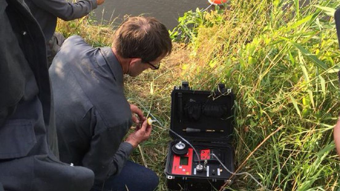 Een monteur onderzoekt het gaslek in de leiding die door het Winschoterdiep loopt.