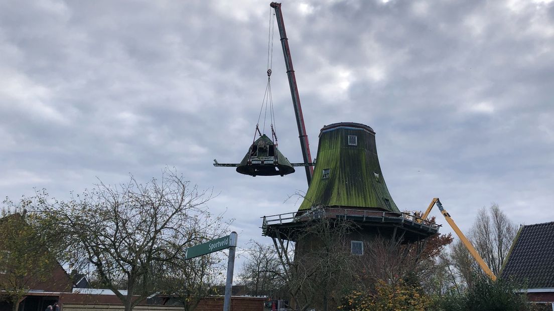 Een hijskraan takelt de kap van de molen