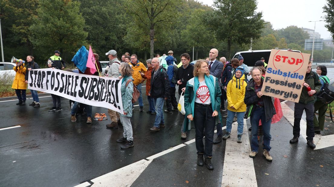 De demonstranten dragen spandoeken met leuzen tegen de fossiele brandstofindustrie