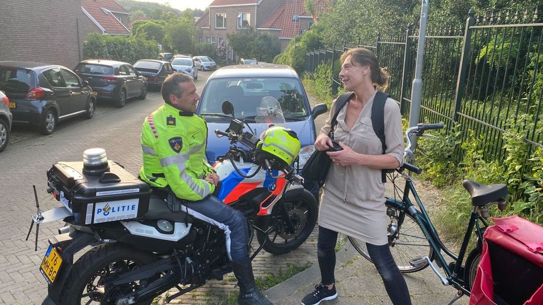 Een agent op de motor in gesprek met een van de buurtbewoners.