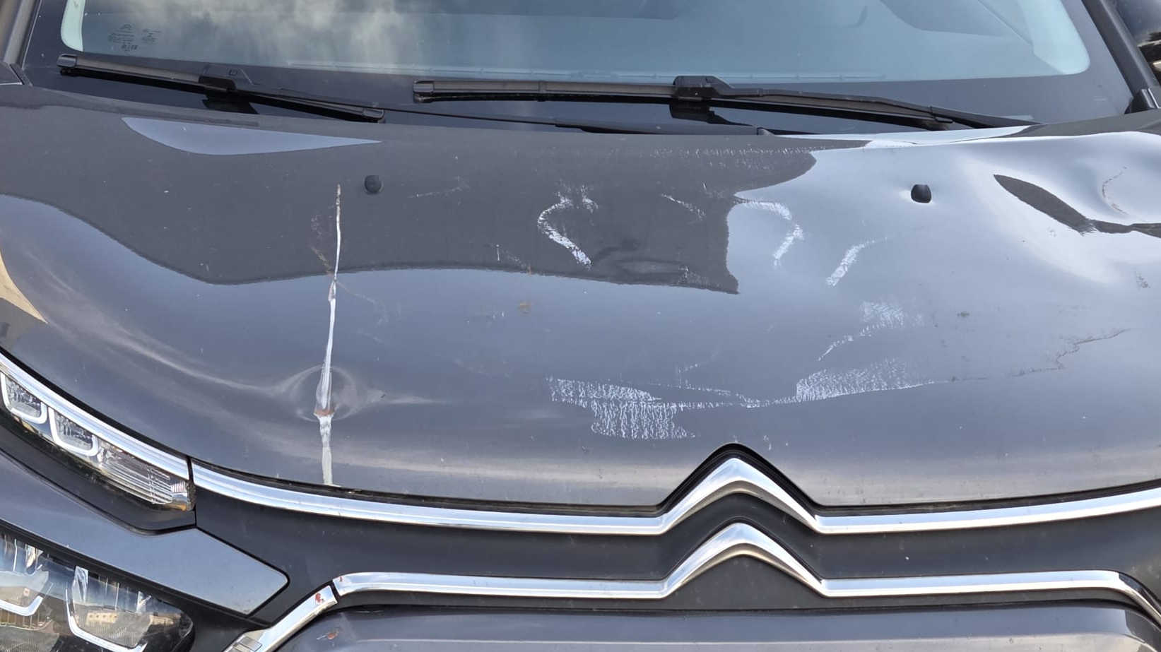 Krassen en deuken in de auto van Ellen van de slagboom van de brug.