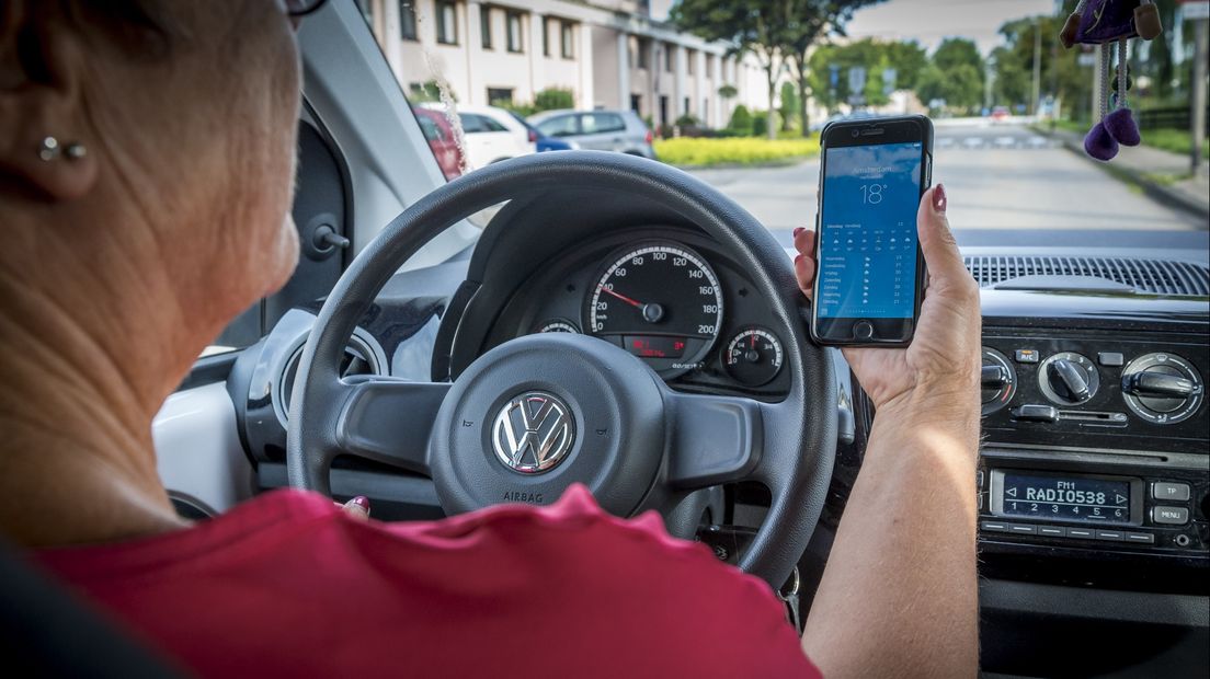Een automobilist kijkt op haar telefoon achter het stuur