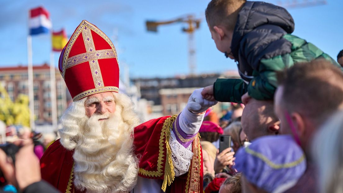 Sinterklaas geeft kinderen een boks na aankomst in de haven van Scheveningen