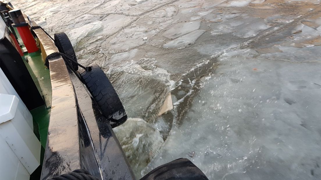 De ijsbreker snijdt door het ijs op de Delftse Schie 