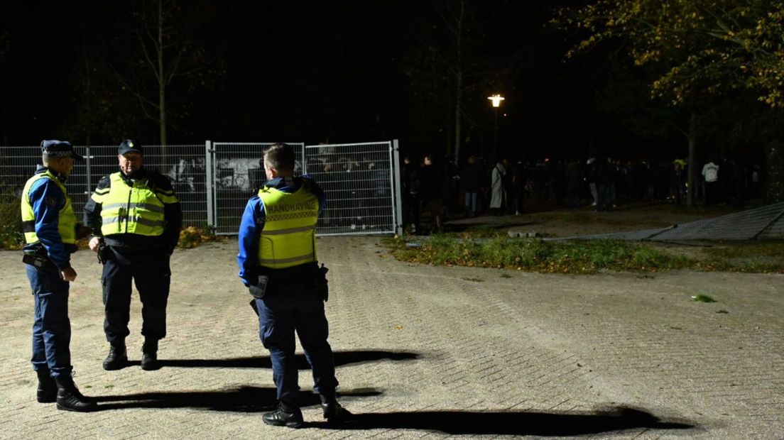 Handhavers bij het platgedrukte hek op de Drafbaan, nadat de rust weer is tgeruggekeerd