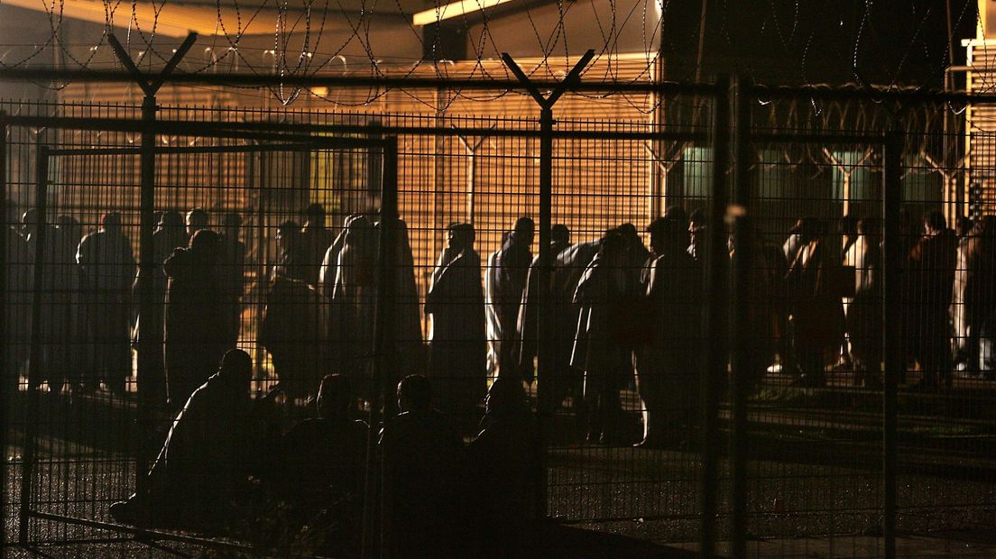 Door brand in het cellencomplex op Schiphol staan gevangenen in 2005 met dekens om zich heen te wachten op vervoer naar een andere plek