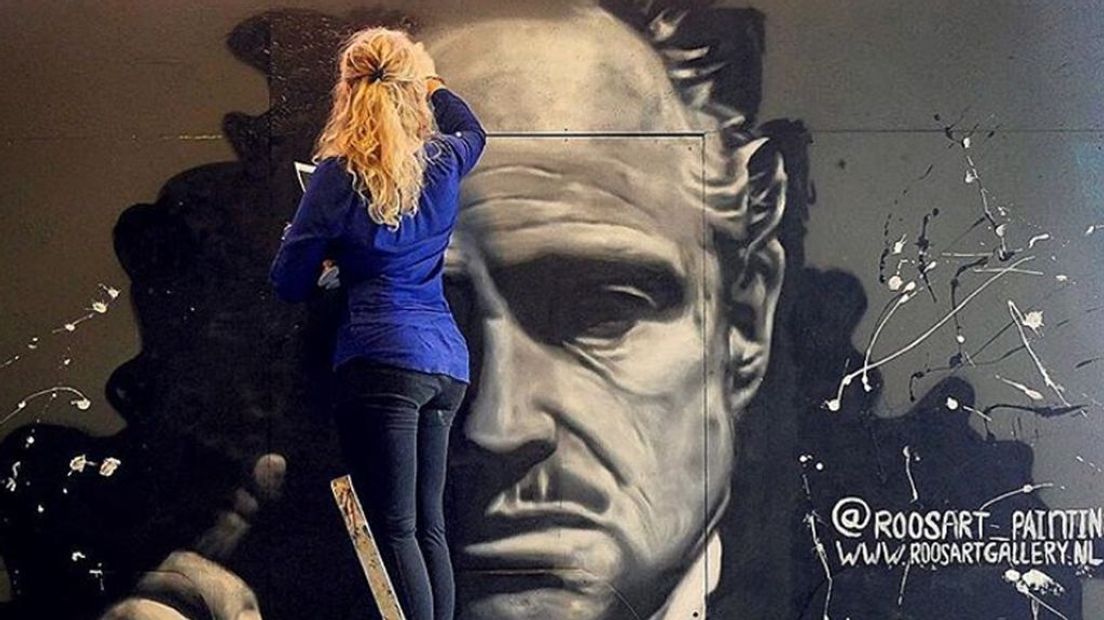 Roos aan het werk met een muurschildering over The Godfather