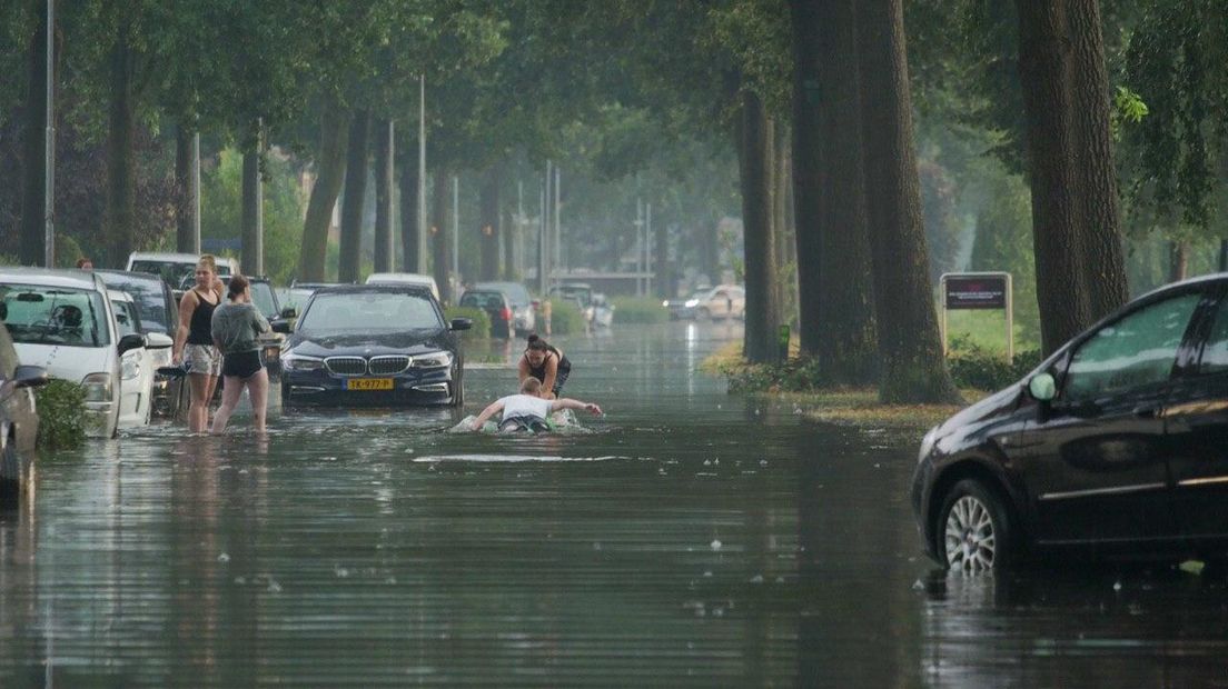 Lekker met je opblaaskrokodil door de straat na hoosbui.