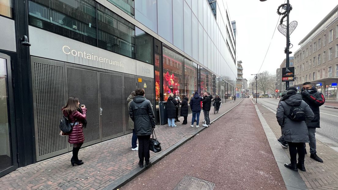 Medewerkers wachten bij de personeelsingang van de Bijenkorf.