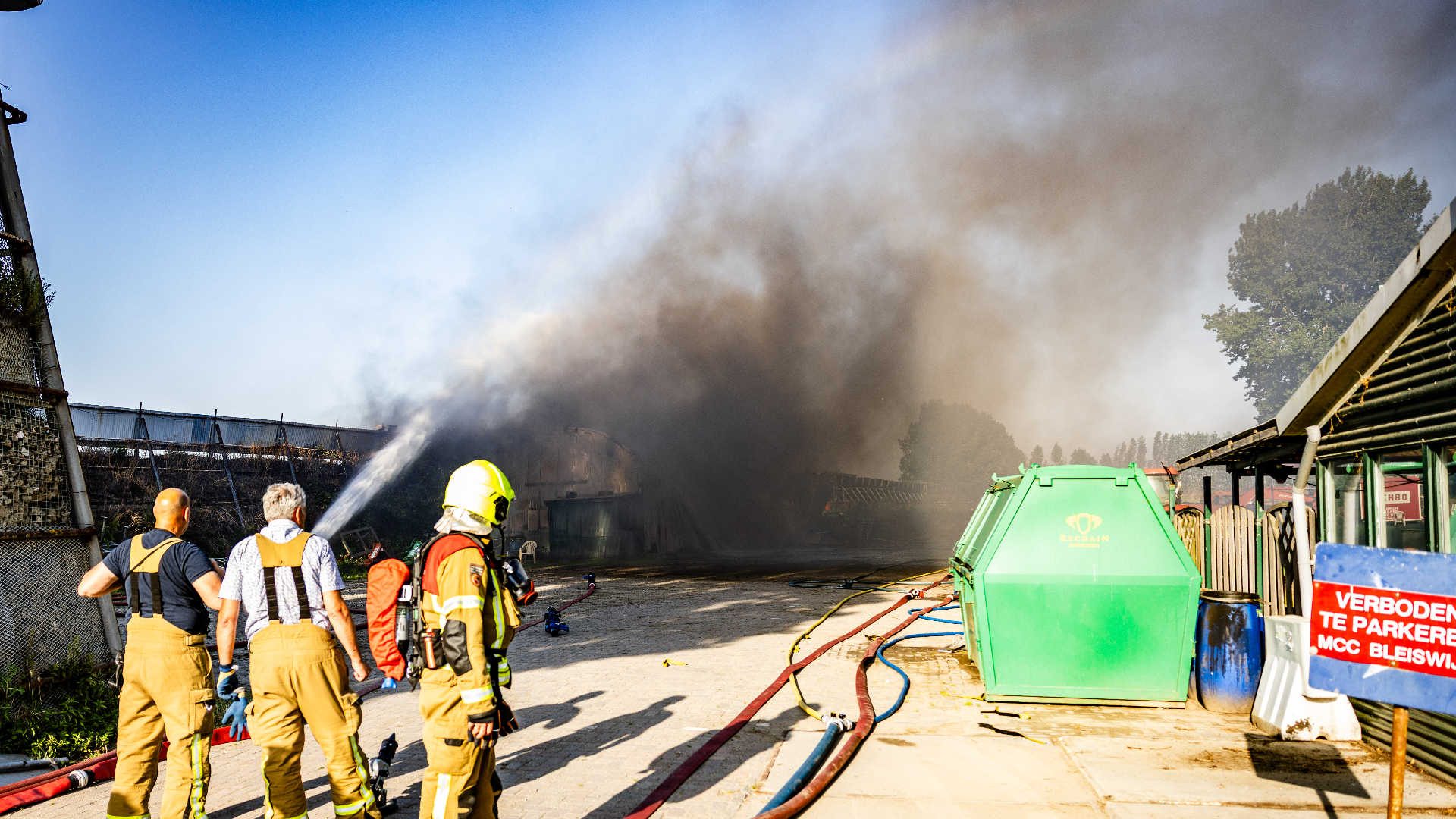 De brand woedt in een loods en zorgt voor veel rook.