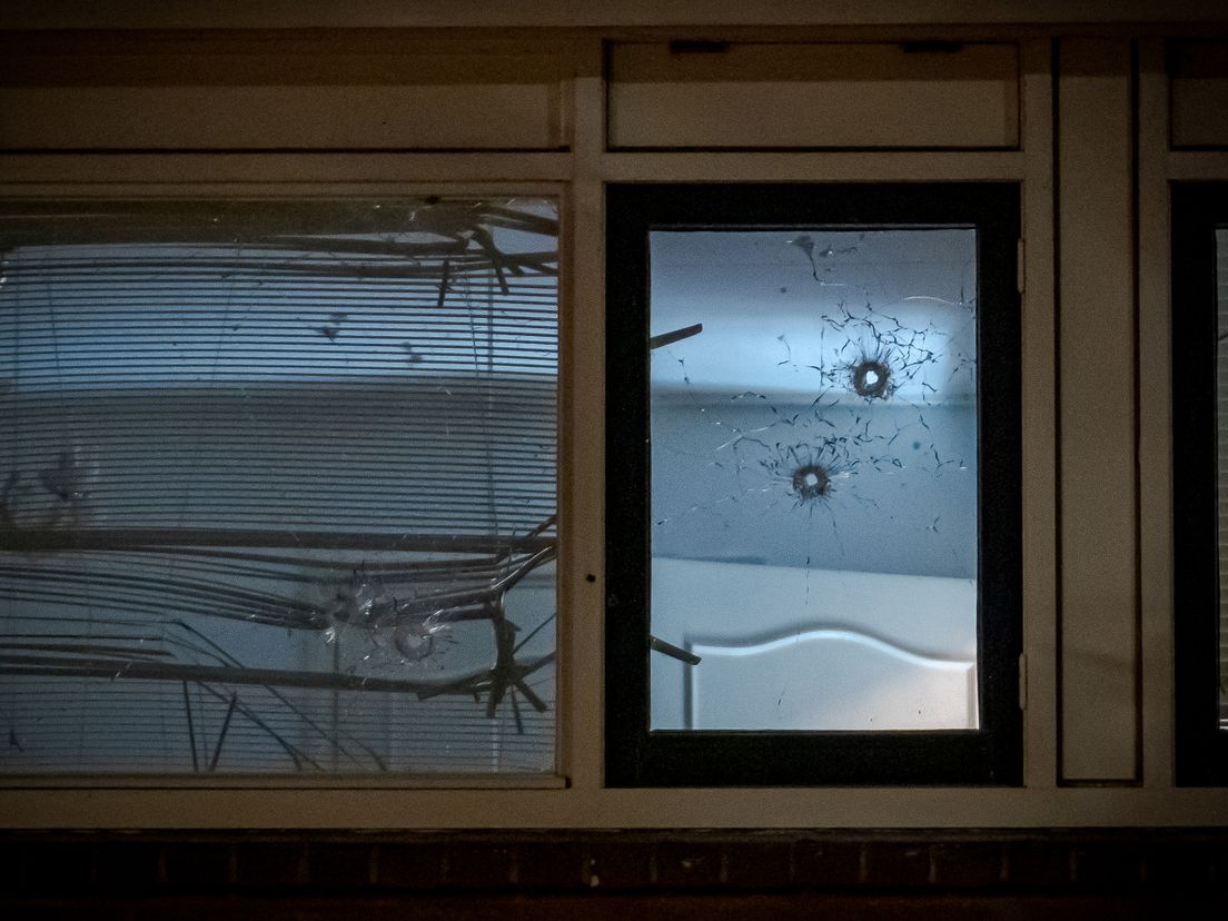 Kogelgaten in een raam van het huis.
