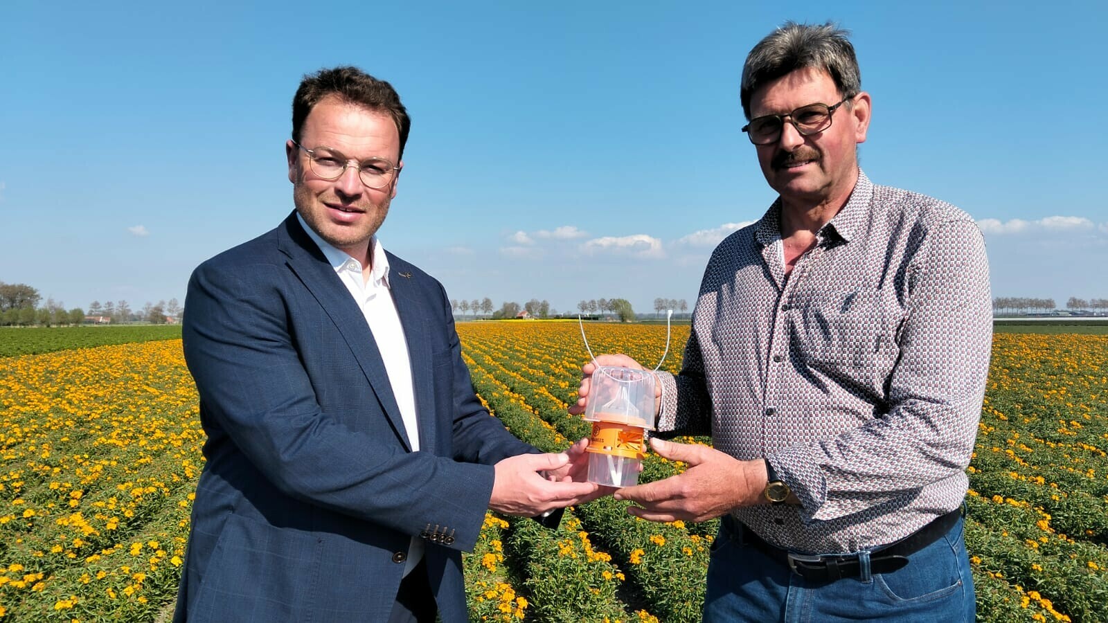 Wethouder Corniel van Leeuwen overhandigt een lokdoos aan Leen Bijnagte van de bloemzaadstudieclub Tholen