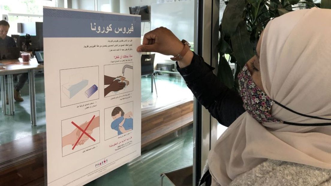 Naima Tabali hangt een voorlichtingsposter in het Arabisch op.