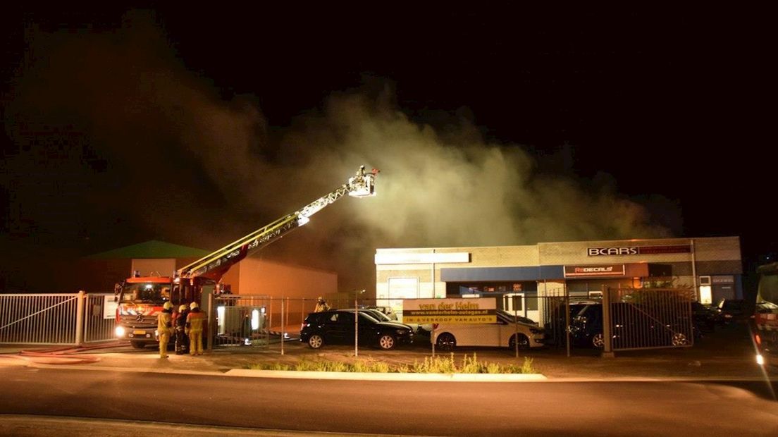 Vlammen slaan uit het dak van autobedrijf Bcars in Hengelo