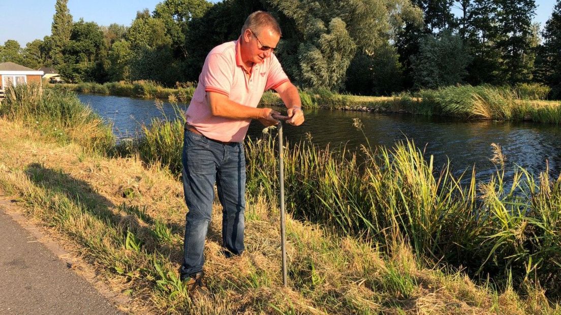 Waterschapsmedewerker Erik Schuringa meet het vochtpeil van een dijk met een handboor