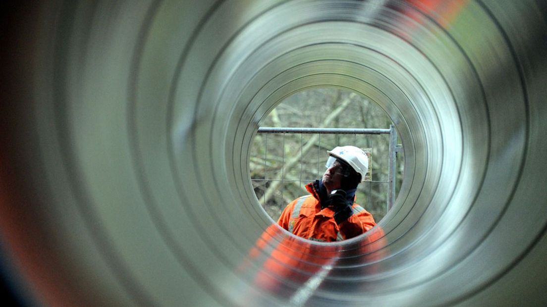 Een bouwvakker inspecteert een gasleiding.