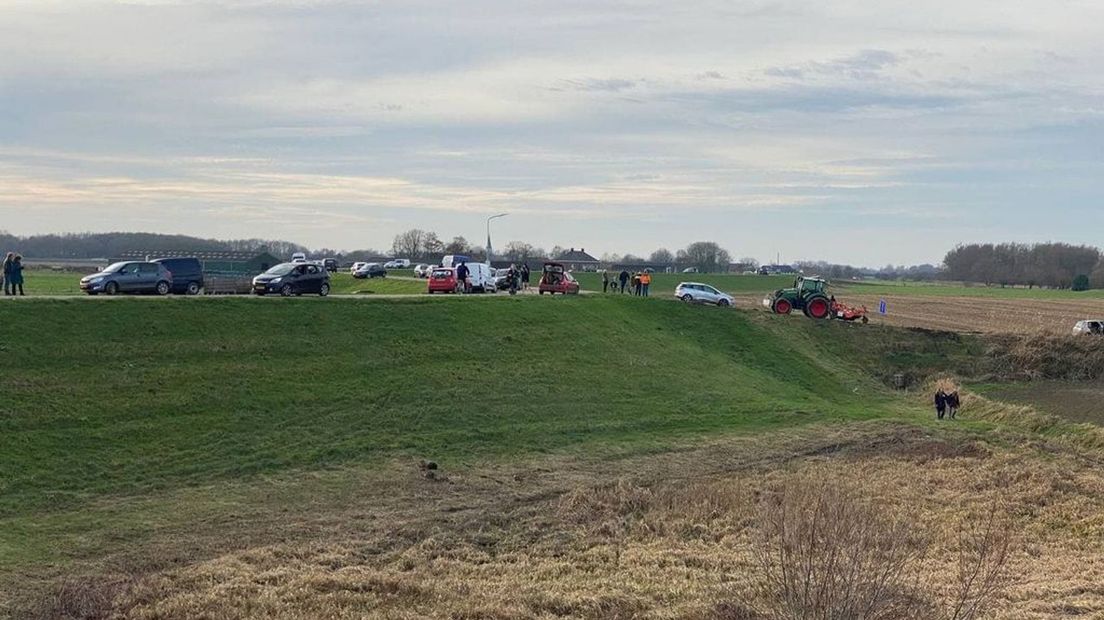 Op de dijk staan veel geparkeerde auto's.