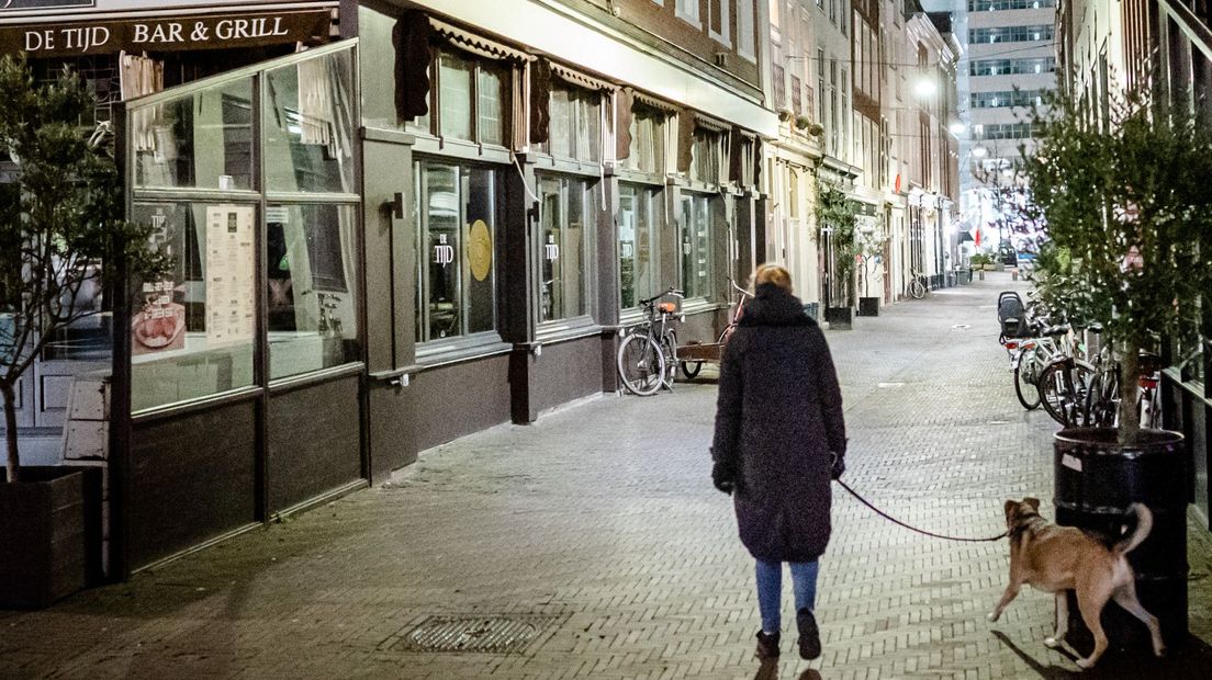 Een vrouw laat haar hond uit tijdens de avondklok